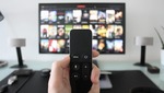 Una persona sujeta un mando para cambiar de canal en su televisor 4K