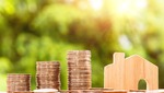 Tres montones de monedas se sitúan a la izquierda de una casa de madera