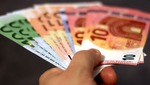 Una mano sujeta varios billetes (euros)